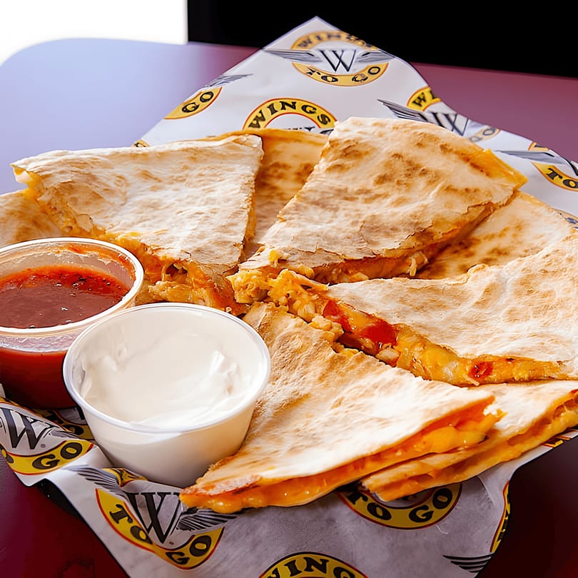 Chicken quesadilla slices with melted cheese, salsa, and sour cream in a basket from Wings To Go.