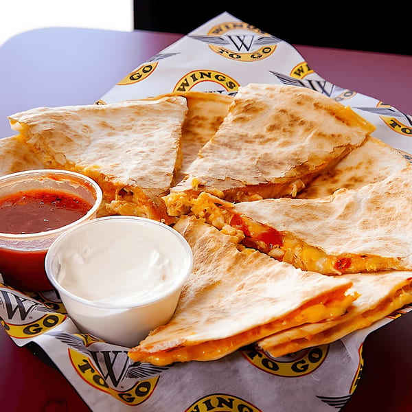 Wings To Go quesadilla slices with melted cheese, salsa, and sour cream in a basket.
