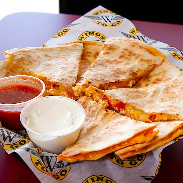 Wings To Go quesadilla with melted cheese, salsa, and sour cream in a branded basket.